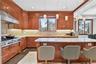 Wood cabinetry, light-toned backsplash, stainless steel range with hood, island with light-toned countertop, and pendant lighting