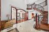 Grand entryway featuring a curved staircase with ornate ironwork and wood-finish treads, a coffered ceiling, and a formal dining space with hardwood f