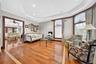 Hardwood flooring with a decorative inlay, tray ceiling with recessed lighting, and arched windows with detailed muntins