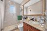 Framed wall mirror, single vanity with wood-finish cabinetry, granite countertop, and integrated sink