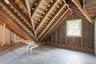 Exposed wood rafters, painted wood flooring, and a white-framed window
