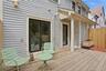 Expansive wood deck with light gray siding, privacy fencing, and dual exterior light fixtures