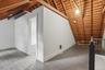 Exposed wood rafter ceiling, painted wood flooring, white painted walls, and an interior doorway