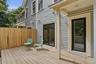 Expansive wood deck with a privacy fence, two exterior doors, and a covered porch area
