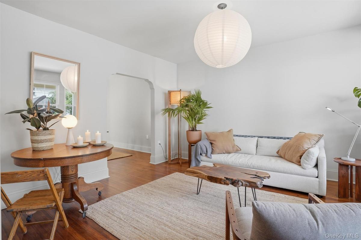 Hardwood flooring, arched doorway, recessed wall mirror, white ceiling, and a large circular pendant light fixture