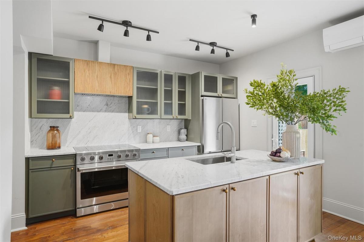 Kitchen featuring a center island, stainless steel appliances, wood-finish flooring, white countertops, and track lighting