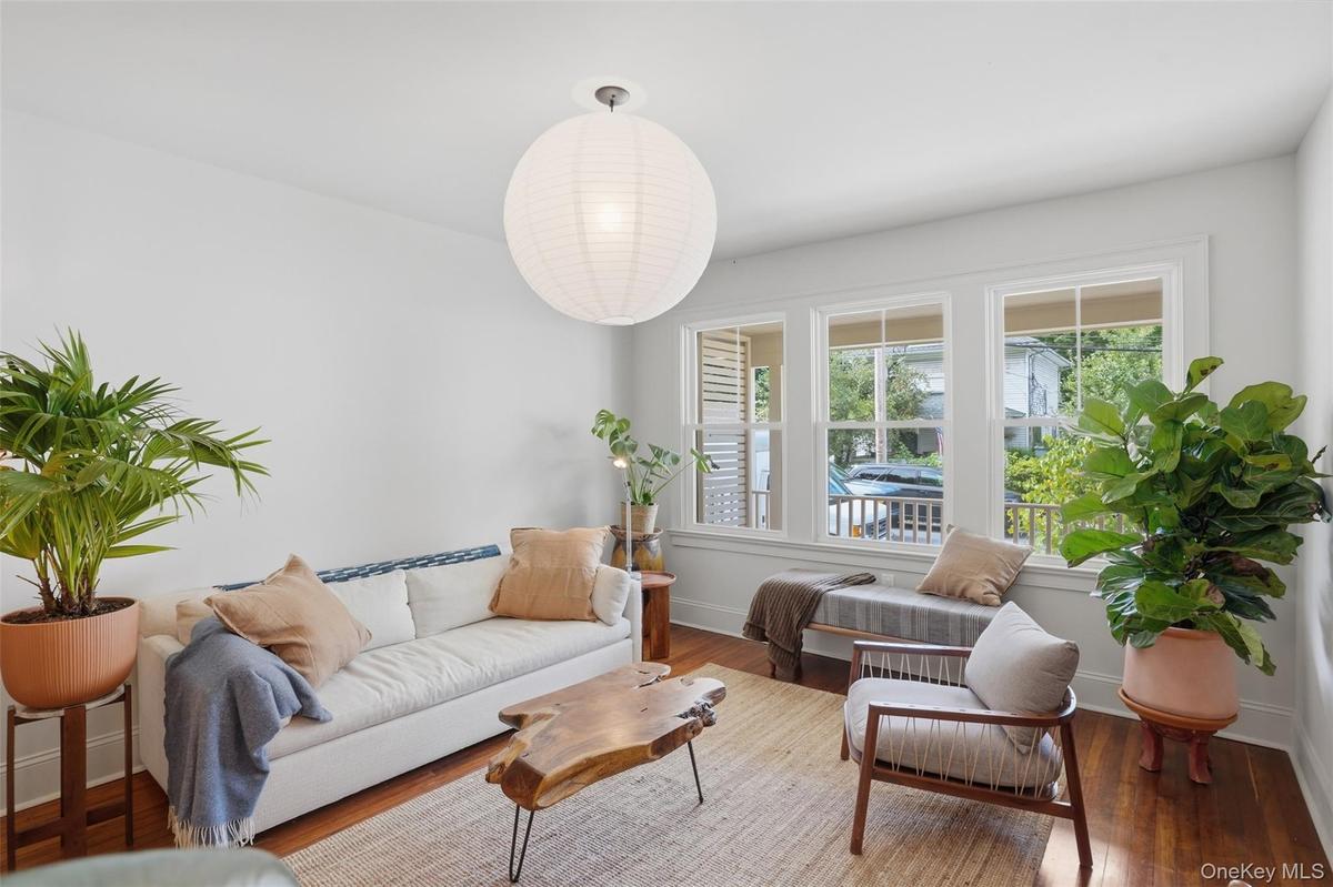 Hardwood flooring, white walls, triple window unit, white trim, and a contemporary ceiling fixture