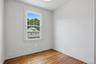 Hardwood flooring, painted walls, window with white trim, and a ceiling-mounted light fixture
