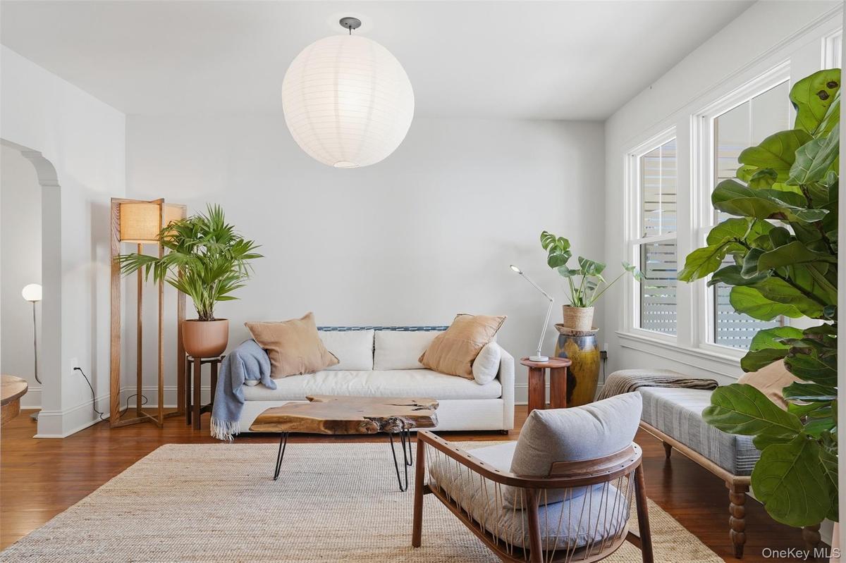 Hardwood flooring, arched doorway, large windows, ceiling-mounted light fixture, light gray wall color