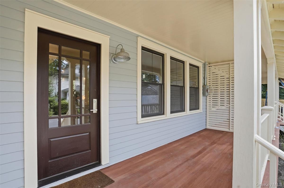 Covered porch with wood-finish flooring, light blue siding, and white trim accents