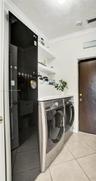 LAUNDRY AREA FEATURES WASHER, DRYER AND STEAM CLOTHING CARE SYSTEM TO STEAM, DEODORIZE AND SANITIZE CLOTHES, BLANKETS, TOYS. DOOR LEADING TO STORAGE/U
