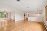 Hardwood flooring throughout, with a semi-open floor plan, a ceiling fan with integrated lighting, and  large windows