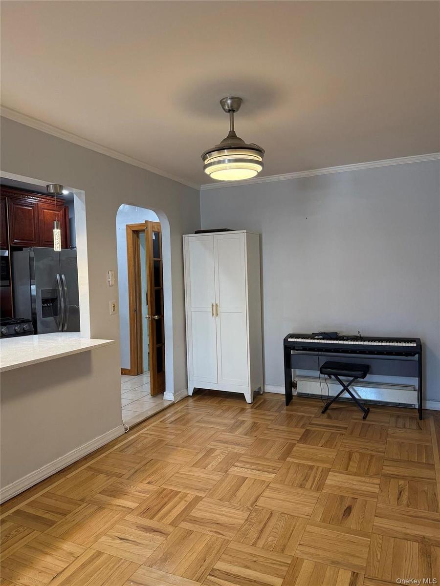 Parquet wood flooring, a ceiling-mounted light fixture, and an arched entryway