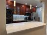 Kitchen featuring light-toned countertops, dark wood-finish cabinetry, stainless steel appliances, and a subway tile backsplash