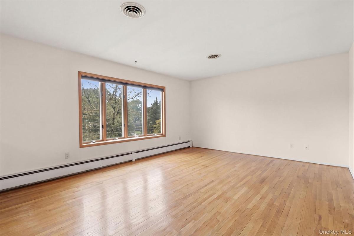 Expansive interior space featuring wood flooring, a multi-pane window with wood-finish trim,