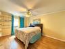 Wood-finish flooring, built-in shelving, window with blinds, and ceiling fan with integrated lighting