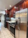 Cherry wood-finish cabinetry, stainless steel appliances, tile flooring, and a subway tile backsplash