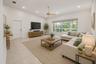 Vaulted ceilings enhance this living space featuring light-toned tile flooring, recessed lighting, and a prominent multi-pane window