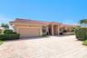 Mediterranean-style exterior featuring a clay tile roof, stucco finish, paver driveway, two-car garage, and established landscaping