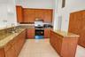 Kitchen featuring extensive wood cabinetry, granite countertops, a central island, stainless steel appliances, and tiled flooring