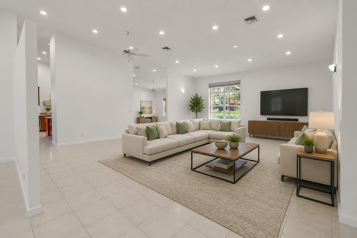 Spacious living area featuring neutral tile flooring, recessed lighting, and a ceiling fan