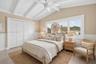 Large guest bedroom upstairs w/ views to front of house, beamed ceiling. Virtually Staged.