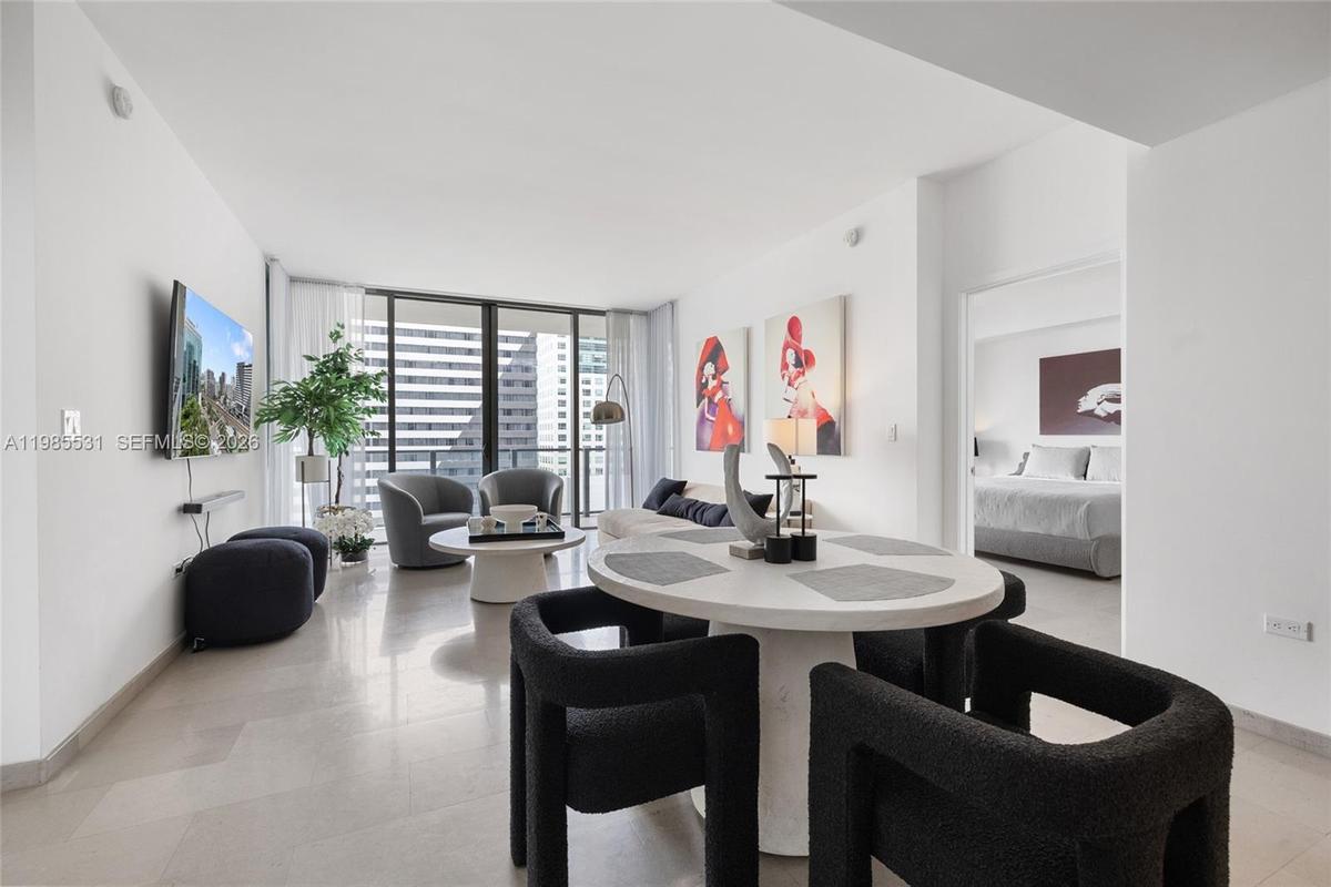 Open-concept interior featuring large-format tile flooring, recessed ceiling lighting, and a modern kitchen with flat-panel cabinetry and stainless st