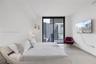 Floor-to-ceiling glass door, neutral stone-finish tile flooring, and integrated wall-mounted lighting