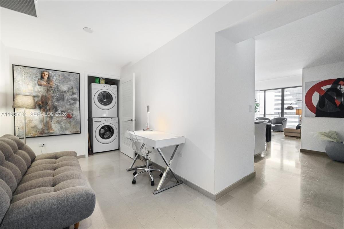 Modern kitchen featuring sleek white flat-panel cabinetry, stone countertops, a stainless steel under-counter wine refrigerator, a gray tile backsplas