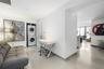 Modern kitchen featuring sleek white flat-panel cabinetry, stone countertops, a stainless steel under-counter wine refrigerator, a gray tile backsplas