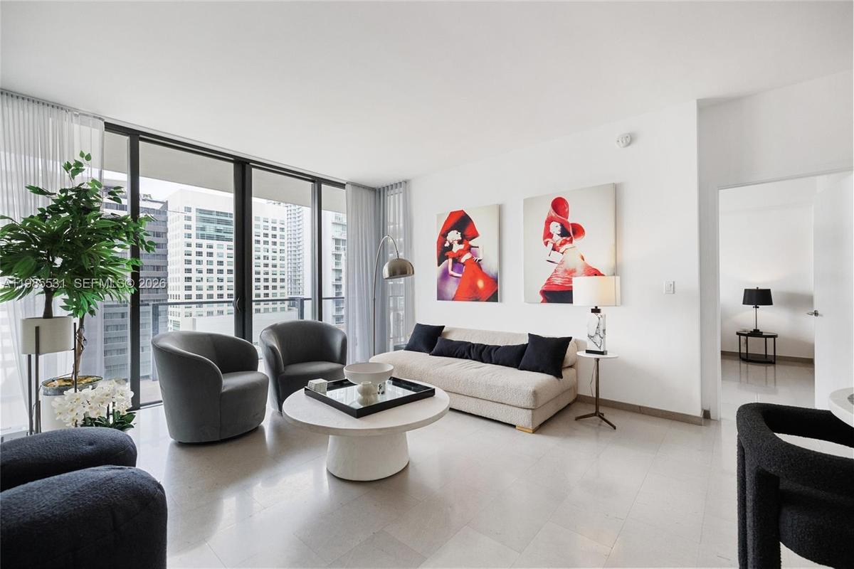 Floor-to-ceiling glass wall, private balcony, and light-toned tile flooring throughout