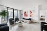 Floor-to-ceiling glass wall, private balcony, and light-toned tile flooring throughout