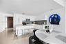 Neutral-toned stone flooring throughout, smooth white wall finishes, and a solid-core door featuring a louvered panel