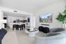 Open-concept living space featuring high-gloss white cabinetry, stone-finish flooring, and floor-to-ceiling windows