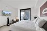Covered balcony featuring wood-finish flooring, glass panel railings, and full-height sliding glass doors
