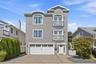Three-story home with stone accents, featuring a paver driveway, and Juliette balconies