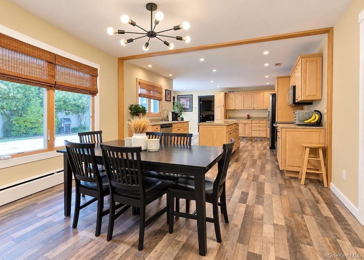Open-concept dining area with wood-finish flooring, a contemporary chandelier, and large windows