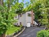 Ai Generated Two-story siding exterior with a prominent brick chimney, attached garage, and a paved driveway