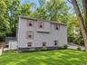 Exterior siding with multiple windows, a rear deck, a paved driveway, and established landscaping