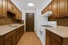 Kitchen with tasteful backsplash, white gas range, under cabinet range hood, and brown cabinets