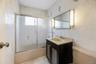 Full bathroom featuring enclosed tub / shower combo, vanity, and tile walls