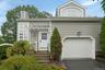 Siding exterior with a paneled garage door, arched window, and a white front entry door with an overhead pergola