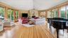 Expansive, sunlit great room with stone fireplace and exit to personal greenhouse.