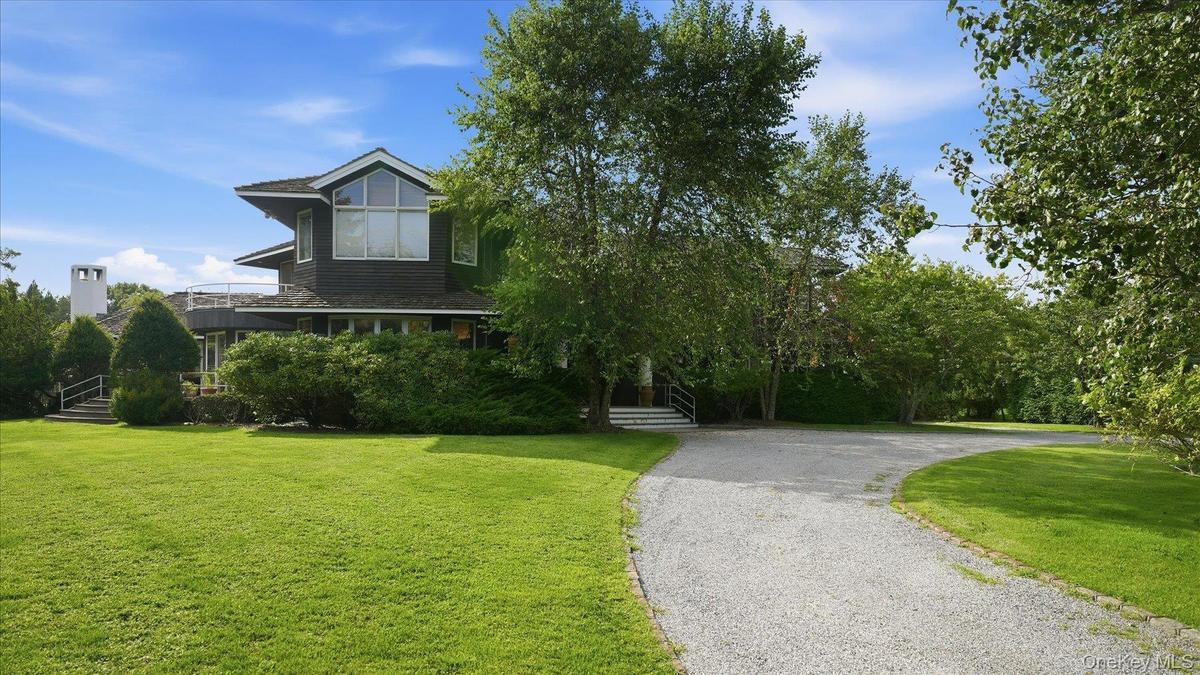Front: long driveway with home behind row of mature landscaping