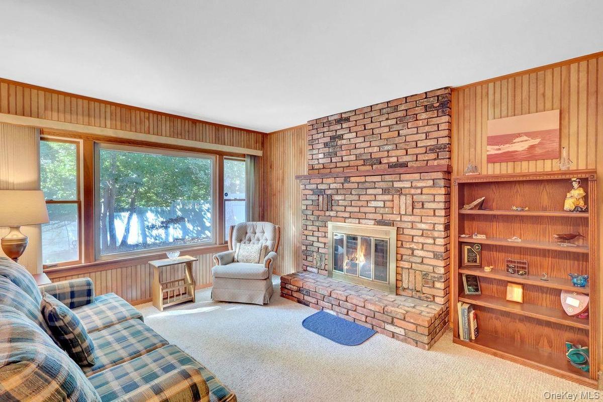 Brick fireplace with hearth,  and a large window over looking  the yard.