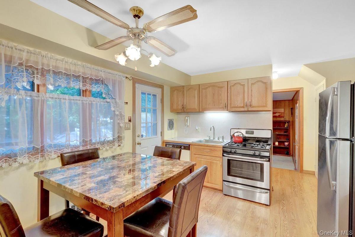 Natural wood-finish flooring, light-toned cabinetry, stainless steel range, and stainless steel refrigerator