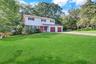 Two-story Colonial with white shake siding and brick accents, featuring a two-car garage duel driveway, on a corner lot.