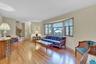 Hardwood flooring throughout, bay window with multiple panes, staircase with ornamental metal railing, and neutral wall tones