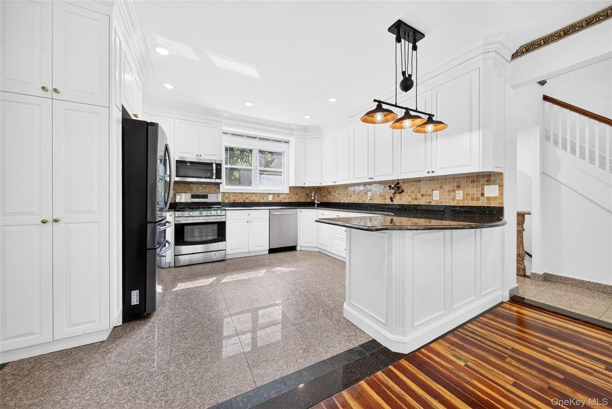 White kitchen cabinetry featuring a mosaic tile backsplash and dark countertops