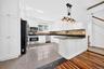White kitchen cabinetry featuring a mosaic tile backsplash and dark countertops